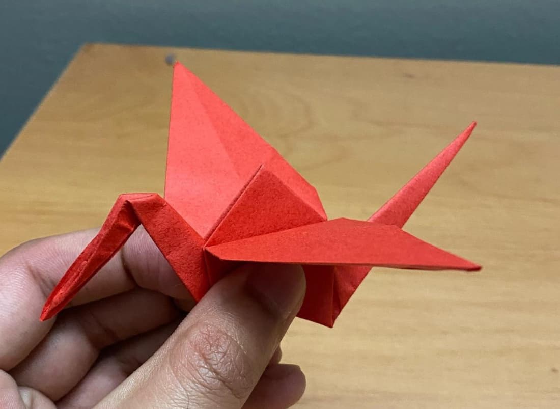 A red paper crane held in hand