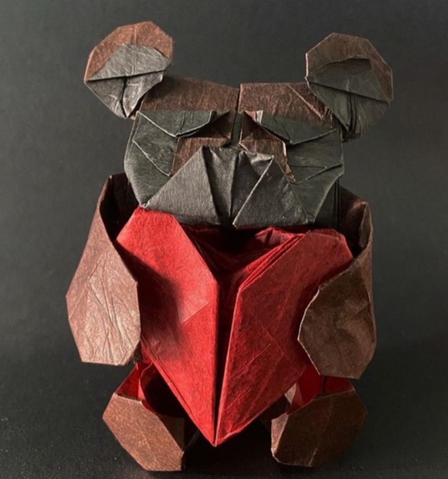 A brown origami bear holding a red heart